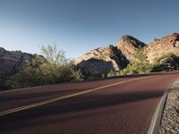 an empty road with mountains in the background of it and no one at all on the side