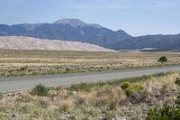 an open desert with a large mountains in the background a road is empty and there is a sign in the foreground that says