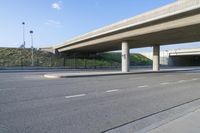 an empty street with a very overpass in the distance and an empty road underneath