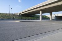 an empty street with a very overpass in the distance and an empty road underneath