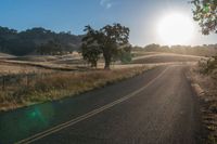 the sun shines brightly on a empty road in the countryside of southern california, usa