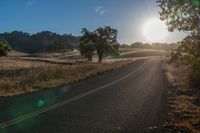 the sun shines brightly on a empty road in the countryside of southern california, usa