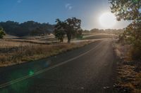 the sun shines brightly on a empty road in the countryside of southern california, usa