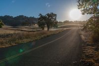 the sun shines brightly on a empty road in the countryside of southern california, usa