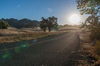 the sun shines brightly on a empty road in the countryside of southern california, usa