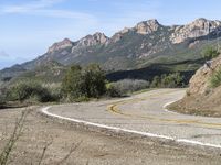 an empty road near two yellow lines that go through the center of the curve on the mountain