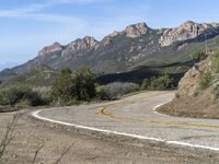 an empty road near two yellow lines that go through the center of the curve on the mountain