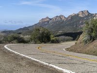 an empty road near two yellow lines that go through the center of the curve on the mountain