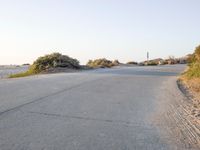 an empty road in the desert with no traffic on it, on the beach with many shrubs
