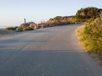 an empty road in the desert with no traffic on it, on the beach with many shrubs