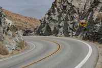 a road is empty near some rocks and cliffs in the desert with an arrow painted on it