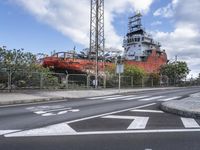 a large boat sits in the middle of an empty road at a dockside area