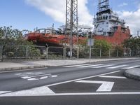 a large boat sits in the middle of an empty road at a dockside area