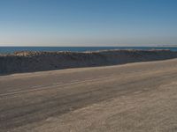 a person riding a bike down an empty road near the ocean in a sunny day