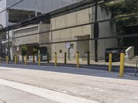 the side of an empty road is covered by fencing and parking meters as a man rides his scooter down it