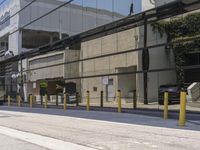 the side of an empty road is covered by fencing and parking meters as a man rides his scooter down it