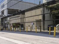 the side of an empty road is covered by fencing and parking meters as a man rides his scooter down it