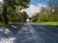 an empty road with trees and bushes in the foreground while it is almost empty