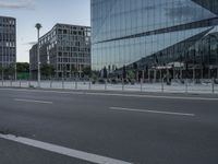 the empty road is deserted in front of the glass buildings of this business building that is across from one another