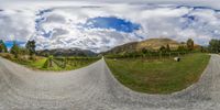 this is a 360 - ray photograph of an empty road and a green field under a cloudy sky