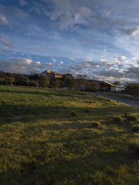 an empty road and green grass on a cloudy day in the suburbs of an urban area