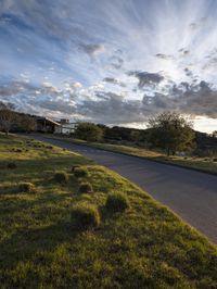 an empty road and green grass on a cloudy day in the suburbs of an urban area