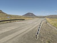 a road with no cars or vehicles on it going past the mountains and grass on the other side