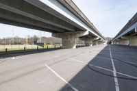 the empty road beside the roadway under an overpass of a highway bridge and soccer field