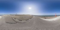 an empty road with cars turning as if in a fish eye view to the beach