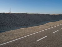 an empty road with several markings on the side and sand up to the side of it