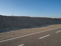 an empty road with several markings on the side and sand up to the side of it