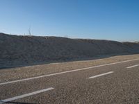 an empty road with several markings on the side and sand up to the side of it