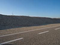 an empty road with several markings on the side and sand up to the side of it