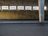 a parking garage with yellow polka dot tiles on the wall and an empty road in front