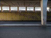 a parking garage with yellow polka dot tiles on the wall and an empty road in front