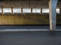 a parking garage with yellow polka dot tiles on the wall and an empty road in front