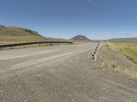 the empty road is near the grassy hills and mountains with signs on it along a mountain