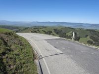 an empty road with mountains in the distance and no traffic sign at the end of it