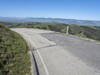 an empty road with mountains in the distance and no traffic sign at the end of it