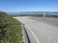 an empty road with mountains in the distance and no traffic sign at the end of it