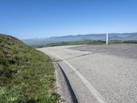 an empty road with mountains in the distance and no traffic sign at the end of it