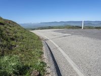 an empty road with mountains in the distance and no traffic sign at the end of it