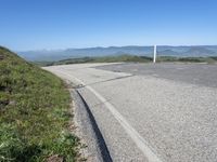 an empty road with mountains in the distance and no traffic sign at the end of it