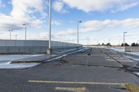 yellow paint marking the way to an empty road in a parking lot in an industrial area of city with white clouds and blue sky above