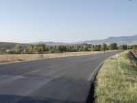 the road is empty and ready to be paved in this field with hills in the distance