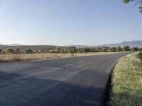 the road is empty and ready to be paved in this field with hills in the distance