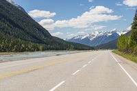 the road is empty on both sides and on the other side there is a lake and mountain range on both sides