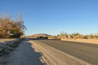 a empty street in the middle of a barren plain with dry grass growing beside it