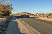 a empty street in the middle of a barren plain with dry grass growing beside it