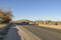 a empty street in the middle of a barren plain with dry grass growing beside it